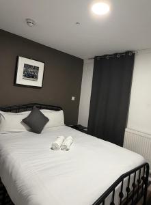 Un dormitorio con una cama con dos pantuflas encima. en TBH Hotel, en Barking