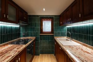 IsolaDOLF - Villa Ombrosa的厨房设有绿色瓷砖墙壁和水槽