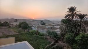 a sunset over a village with palm trees and buildings at Karima house B in Al Aqālitah