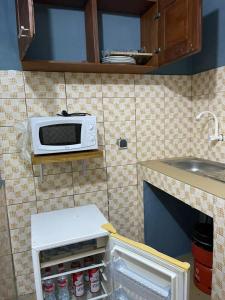 a kitchen with a microwave on a tiled wall at Résidence saint-Gall-H in Ouidah
