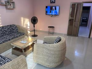 a living room with a couch and chairs and a tv at Résidence saint-Gall-H in Ouidah