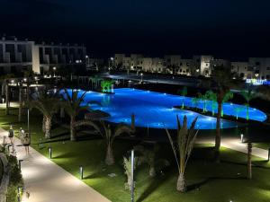 a large blue pool with palm trees at night at CoveDream Studio Cove Garden Sun Valley Esentepe in Aglantzia