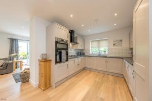 a large kitchen with white cabinets and a hardwood floor at Adwyr-Mynydd in Dinorwic