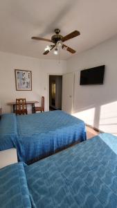 Un dormitorio con una cama azul y un ventilador de techo. en Hotel Internacional Necochea, en Necochea