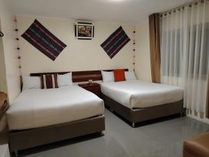 Cusco Imperium House في San Antonio: سريرين في غرفة الفندق مع تنورات