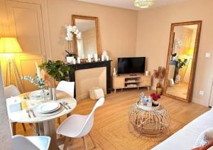 a living room with a table and chairs and a television at Fleur Bohème - Hypercentre République - Parking in Le Mans