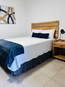 uma cama com lençóis azuis e brancos e uma cabeceira de cama em madeira em Room 7 Ciudad Jardin em San Miguel