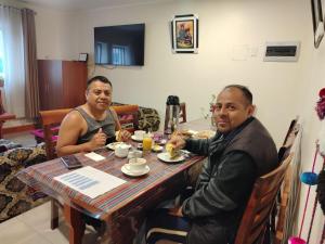 Cusco Imperium House في San Antonio: يجلس رجلان على طاولة لتناول الطعام