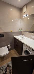 a bathroom with a washing machine and a sink at Łąkowa 7 Apartamenty LUNA Białystok in Skorka