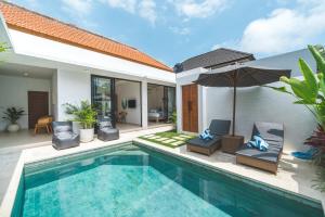 a pool with chairs and an umbrella next to a house at Villa Kusuma 3 Seminyak in Badung