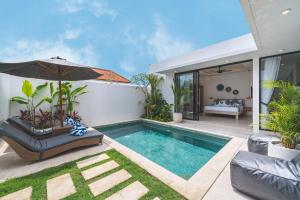 a swimming pool with an umbrella next to a house at Villa Kusuma 3 Seminyak in Badung