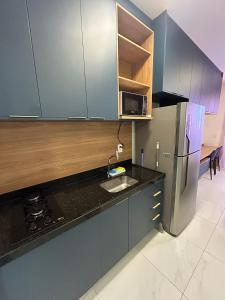 a kitchen with a sink and a refrigerator at Melhores Flats - Elegante a 5 min do mar de Tambaú in João Pessoa