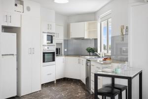 una cucina con armadi bianchi e tavolo nero di Quiet location close to it all a Gold Coast