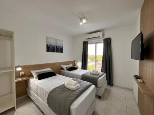 two beds in a hotel room with a television at Vela Villa Apart in Villa Ángela