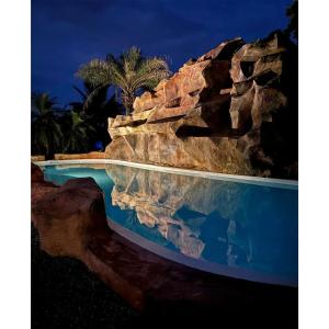 a pool in a resort with a rock wall at My Paradise Chiang Rai in Ban Doi Hang