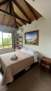 a bedroom with a bed and a large window at Essência da Guarda Surf House in Guarda do Embaú