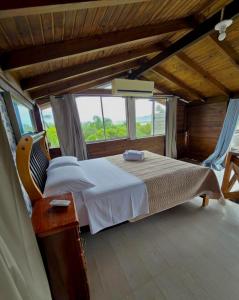 a bedroom with a bed and a large window at Essência da Guarda Surf House in Guarda do Embaú +25 photos