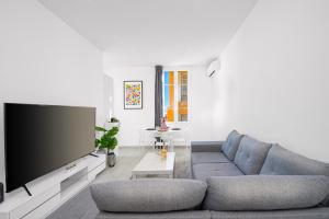 uma sala de estar com um sofá cinzento e uma televisão de ecrã plano em 3P Monaco avec parking em Saint-Antoine