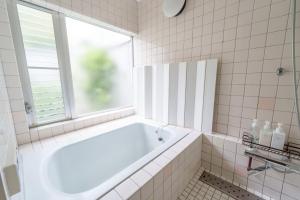 a white bathroom with a tub and a window at SEBARI casa vacation rental in Kushima +14 photos