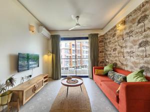 Premium 1BHK Beachside Apartment - Pool, Full Kitchen & Balcony, Candolim في كاندوليم: غرفة معيشة مع أريكة حمراء وتلفزيون