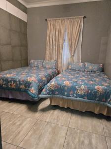 Kelmatic Guesthouse on 5th Ave في روديبورت: سريرين في غرفة بها نافذة