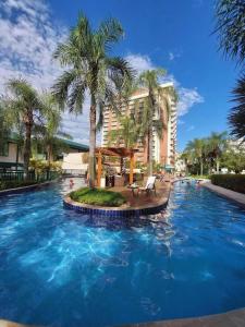 a large pool with palm trees in front of a hotel at Apart hotel Barra First in Rio de Janeiro