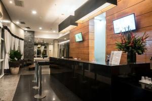 a lobby with a reception counter with flowers on the wall at Apart hotel Barra First in Rio de Janeiro +9 photos