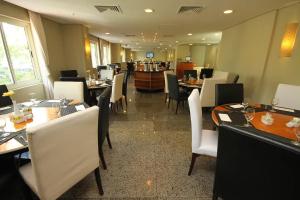 a restaurant with tables and white chairs and a bar at Apart hotel Barra First in Rio de Janeiro