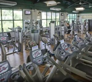 a gym with lots of cardio equipment and a woman in the background at Apart hotel Barra First in Rio de Janeiro