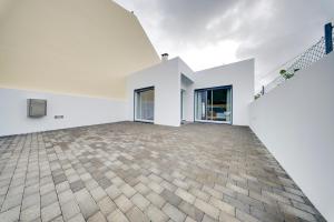 een lege kamer met witte muren en een bakstenen vloer bij C&A Guest House in Furnas +17 foto's