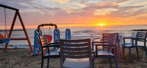 een tafel en stoelen op het strand bij zonsondergang bij PERLA 9- Golem Best apartment in Golem