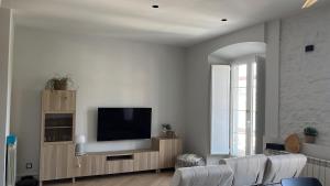 a living room with a television and white walls at Alojamientos Boutique Ribadesella in Ribadesella