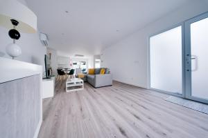 een open woonkamer met witte muren en houten vloeren bij C&A Guest House in Furnas