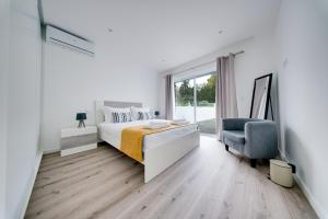 een witte slaapkamer met een bed en een stoel bij C&A Guest House in Furnas