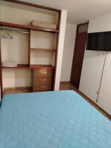 a bedroom with a blue bed and a tv at Agradable Estadía in Trujillo +15 photos