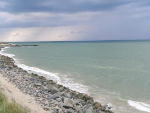 a beach with rocks and the ocean on a cloudy day at 4 person holiday home in Hjørring-By Traum in Lønstrup