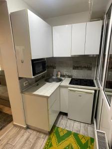 eine kleine Küche mit weißen Schränken und einer Spüle in der Unterkunft LCB Apartments P Victoriei in Ploieşti