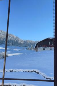 un campo innevato con un edificio sullo sfondo di Appartement rénové au pied des pistes avec piscine, sauna, linge inclus et animaux acceptés a Flumet