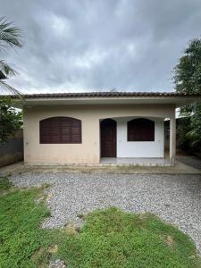 Una pequeña casa blanca con dos puertas de garaje marrones. en Ampla casa em Porto Belo com fácil acesso à Zimbros, en Porto Belo