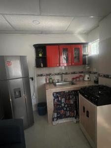 a kitchen with red cabinets and a stainless steel refrigerator at Aparta estudio Santa Marta in Santa Marta +3 photos
