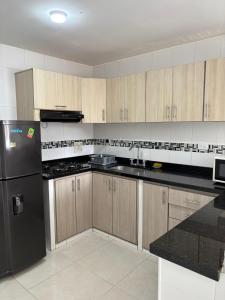 a kitchen with a black refrigerator and wooden cabinets at La Morada del Sur in Floridablanca