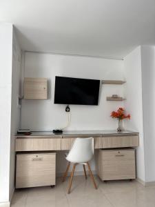 a desk with a television on a wall with a chair at La Morada del Sur in Floridablanca