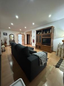 ein Wohnzimmer mit einer schwarzen Couch und einem Fernseher in der Unterkunft Alojamento Luna in Porto Judeu