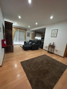 ein Wohnzimmer mit einem schwarzen Sofa und einem Teppich in der Unterkunft Alojamento Luna in Porto Judeu