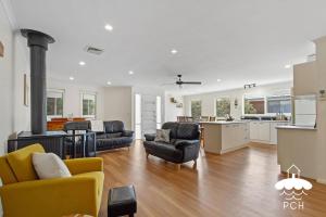 a living room with two chairs and a stove in a kitchen at Wyrallah House - Stay 5 Nights PAY 4 - Jan 1-22 in Lakes Entrance