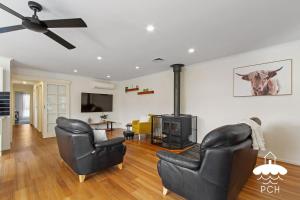 a living room with two chairs and a fireplace at Wyrallah House - Stay 5 Nights PAY 4 - Jan 1-22 in Lakes Entrance
