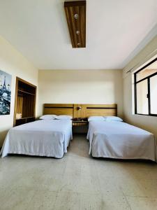 due letti in una stanza con due finestre di Hotel Calvete a Torreón
