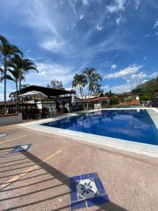 uma piscina azul com palmeiras ao fundo em FINCA HOTEL LAS CABAÑAS DEL Parque em Pueblo Tapao
