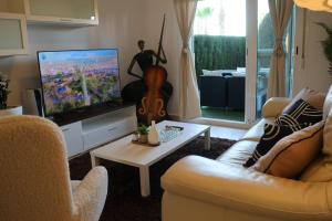een woonkamer met een bank en een tv met een gitaar bij May O'Dea Suite in Orihuela-Costa