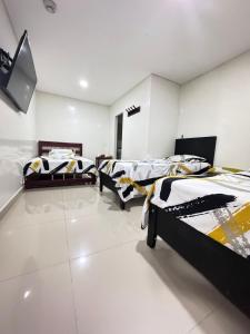 a room with three beds and a tv in it at Hostal la 200 in Floridablanca